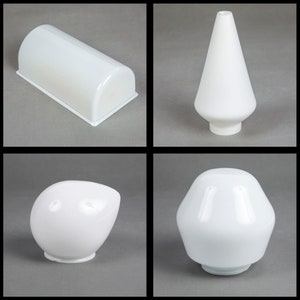 May include: Four white glass lampshades in different shapes. The lampshades are all made of a smooth, opaque glass. The lampshades are all in a neutral white color.