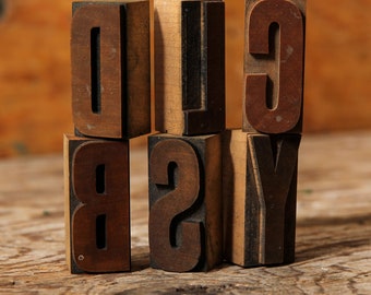 May include: Six wooden letter blocks, each with a different letter, spelling out the word "BOXY". The blocks are brown and have a worn, vintage look.