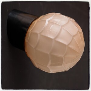 Peut inclure: Un luminaire mural de style vintage avec une base noire et un globe en verre blanc texturé.