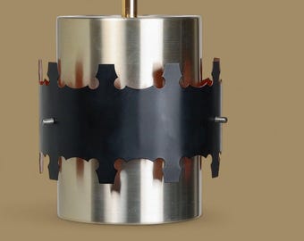 May include: A silver pendant light with a black metal shade and a copper-colored trim. The shade has a decorative, scalloped edge.