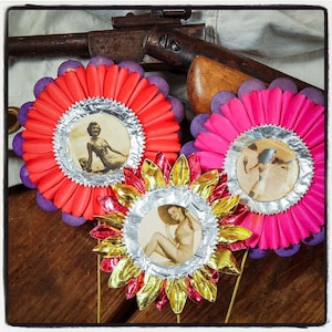 May include: Three paper flowers with silver foil centers and vintage photographs of women in swimsuits. The flowers are red, pink, and yellow with purple accents.