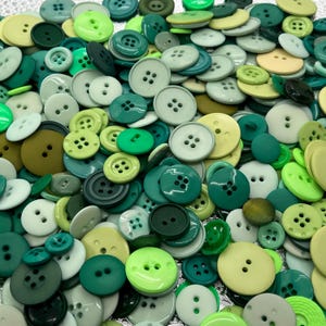 Puede incluir: Una gran colección de botones verdes, verde claro y marrones de varios tamaños y estilos. Los botones están dispuestos en un patrón aleatorio y son perfectos para proyectos de manualidades.