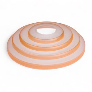 May include: A set of five concentric, translucent, peach-colored glass rings stacked on top of each other.