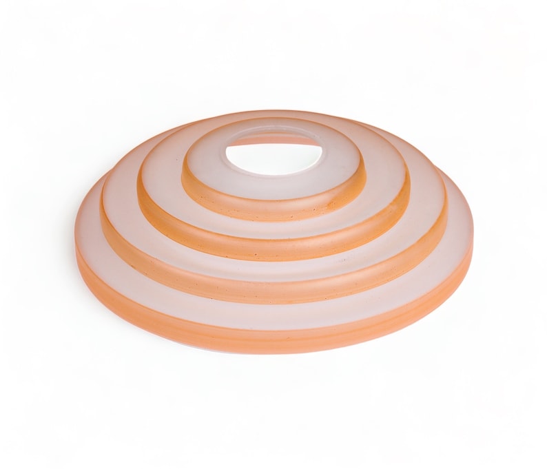 May include: A set of five concentric, translucent, peach-colored glass rings stacked on top of each other.