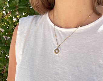 Gold-colored sun pendant necklace with mother-of-pearl plates