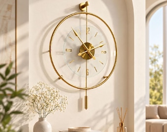 May include: A circular wall clock featuring a gold metal frame and a central transparent glass dial. The clock has gold hands, gold hour markers, and the numbers 12 and 6 in gold. A gold vertical rod extends from the top to a gold pendulum.
