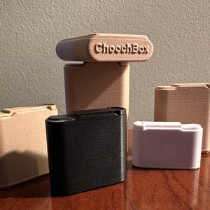 May include: Four small boxes, two beige, one black, and one white. The beige boxes have a raised inscription that reads "ChoochBox".