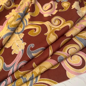 May include: Red fabric with a gold, pink, and blue paisley pattern.