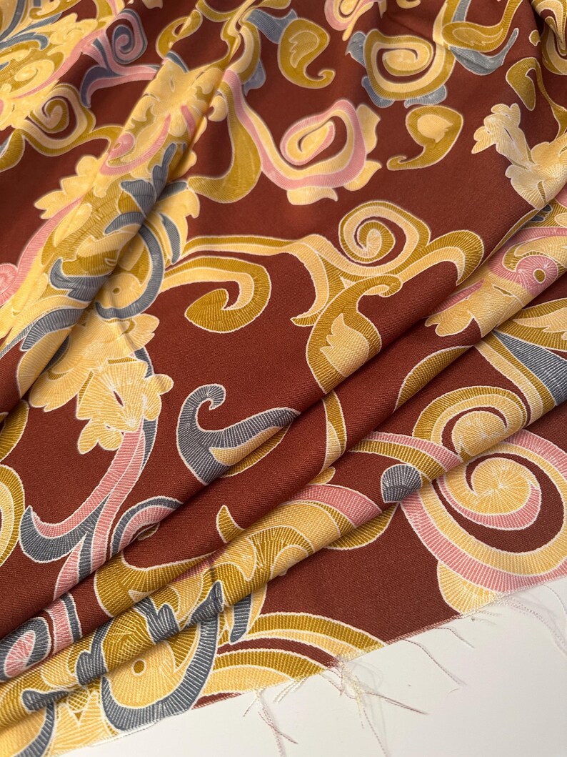 May include: Red fabric with a gold, pink, and blue paisley pattern.