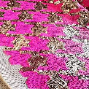 May include: Pink and gold sequined fabric with a geometric pattern. The sequins are arranged in a repeating pattern of small circles and larger, irregular shapes.