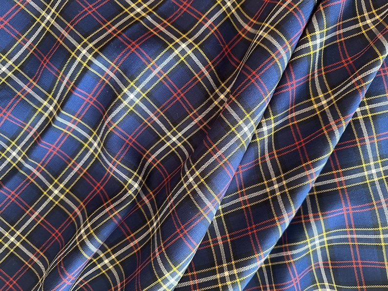 May include: Blue, red, white, and yellow plaid fabric with a woven texture.
