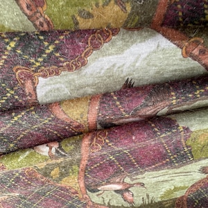 May include: Close-up of fabric with a repeating pattern featuring figures in plaid attire, ducks, and a landscape. The plaid is primarily burgundy, green, and gold. The fabric has a vintage or antique aesthetic.