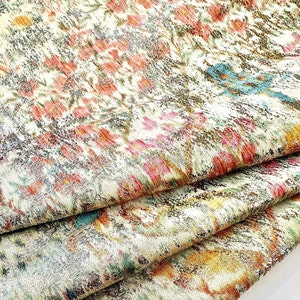 May include: A close-up of a fabric with a colorful floral pattern. The fabric is folded in layers, revealing the intricate details of the design. The colors are vibrant and the pattern is reminiscent of a traditional Persian rug.