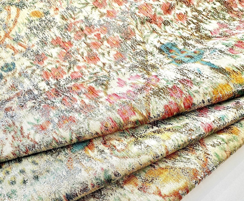 May include: A close-up of a fabric with a colorful floral pattern. The fabric is folded in layers, revealing the intricate details of the design. The colors are vibrant and the pattern is reminiscent of a traditional Persian rug.
