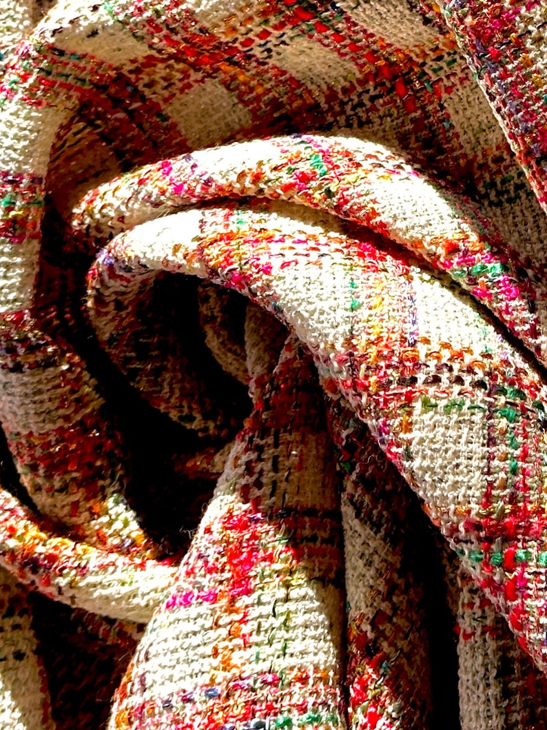Puede incluir: Primer plano de una tela blanca con un estampado de cuadros de colores. La tela est&aacute; doblada y retorcida, creando un efecto de remolino.
