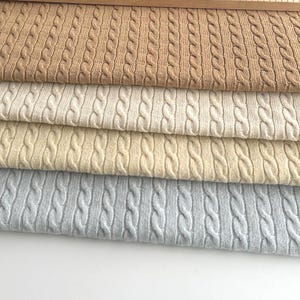 Tejido de punto italiano, con patrón de trenzas, confeccionado en lana virgen y lana de cordero, en 5 colores: capuchino, camel, marfil, marfil claro, azul acero,