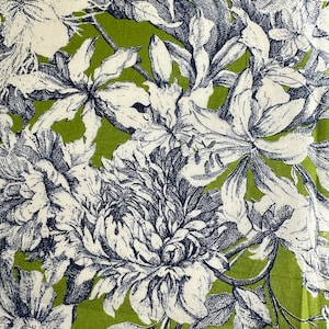 Puede incluir: Una tela verde con un patrón floral blanco y azul. Las flores son grandes y detalladas, con diseños intrincados. La tela es perfecta para manualidades, acolchado o decoración del hogar.