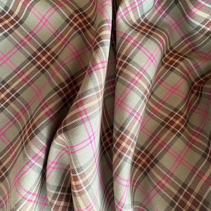 May include: A close-up of a fabric with a plaid pattern in shades of brown, beige, and pink.