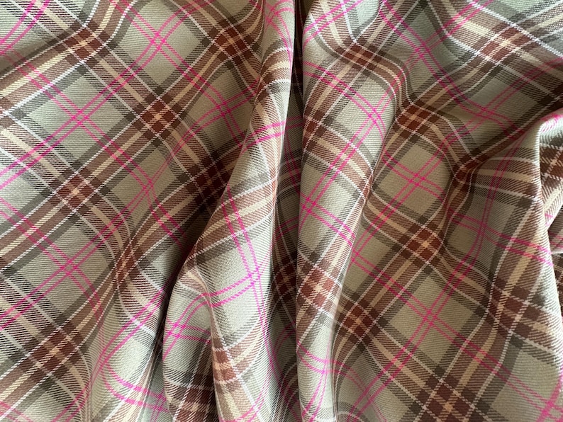 May include: A close-up of a fabric with a plaid pattern in shades of brown, beige, and pink.