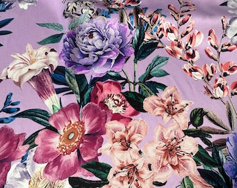 Op de afbeelding: Een paarse achtergrond met een bloemenpatroon met roze, witte en paarse bloemen. De bloemen worden omringd door groene bladeren.
