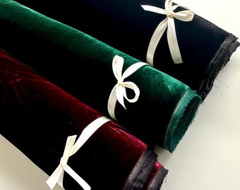 May include: Three rolls of velvet fabric in black, green, and burgundy, tied with white ribbon.