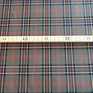 May include: A close-up of a gray, red, and yellow plaid fabric. A ruler is visible at the bottom of the image with markings for 45, 40, 35, 30, and 25.