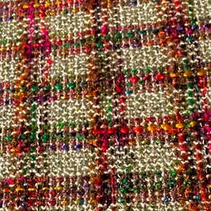 Puede incluir: Primer plano de una tela tejida con un patr&oacute;n de cuadros. La tela es de color beige claro con hilos de rojo, naranja, verde, azul y morado.