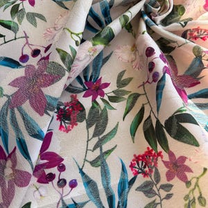 May include: White fabric with a tropical floral print featuring pink, purple, and red flowers, green leaves, and blue accents.