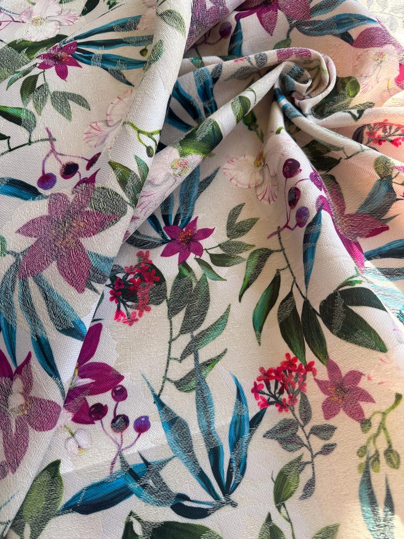 May include: White fabric with a tropical floral print featuring pink, purple, and red flowers, green leaves, and blue accents.