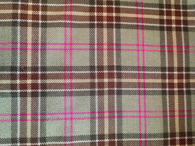 May include: A close-up of a plaid fabric with a green, brown, and white base and pink stripes.
