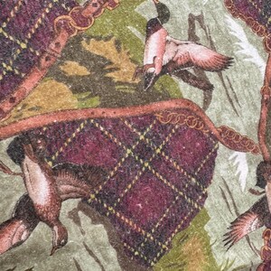 May include: A detailed pattern featuring ducks in flight, set against a backdrop of a green and tan landscape. The design incorporates elements of a burgundy plaid with gold accents and decorative borders, creating a vintage aesthetic.