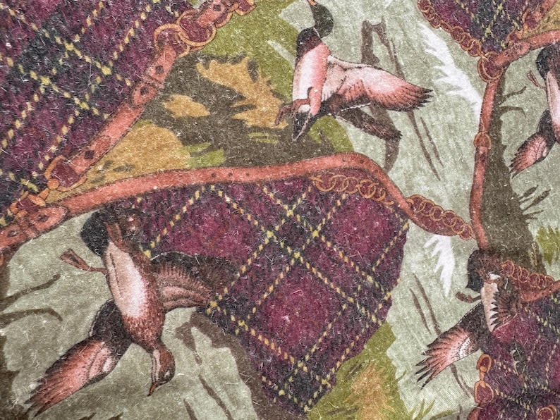 May include: A detailed pattern featuring ducks in flight, set against a backdrop of a green and tan landscape. The design incorporates elements of a burgundy plaid with gold accents and decorative borders, creating a vintage aesthetic.