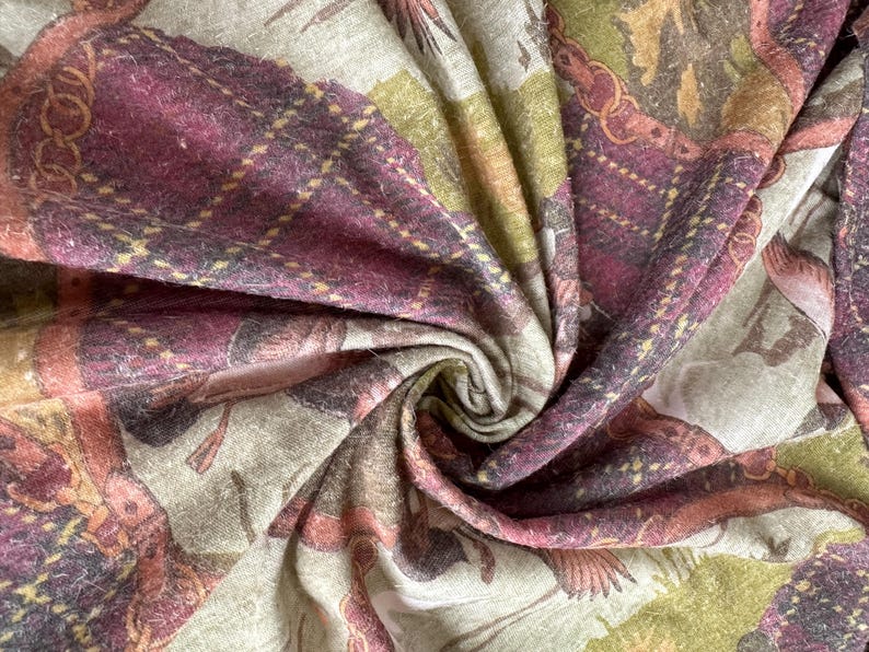 May include: Close-up of a patterned fabric with a swirling design. The fabric features a mix of colors, including burgundy, olive green, and beige. The pattern includes plaid and floral elements, creating a textured and detailed appearance. The fabric appears soft and possibly woven.