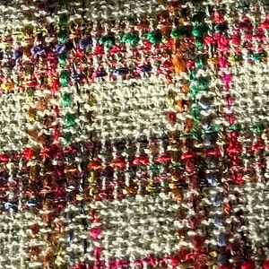 Puede incluir: Primer plano de una tela tejida con una superficie texturizada. La tela es una mezcla de hilos beige, marr&oacute;n, rojo, rosa, verde y azul.