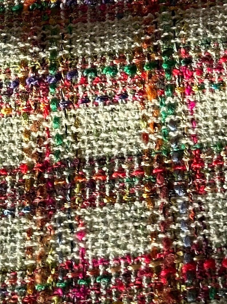 Puede incluir: Primer plano de una tela tejida con una superficie texturizada. La tela es una mezcla de hilos beige, marr&oacute;n, rojo, rosa, verde y azul.