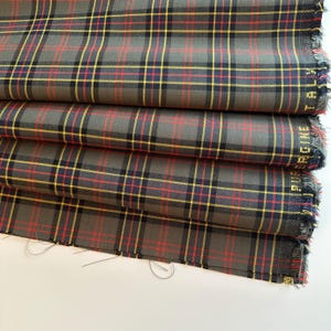 May include: Gray, red, and yellow plaid fabric with a frayed edge.