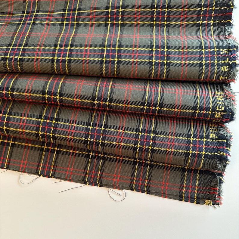 May include: Gray, red, and yellow plaid fabric with a frayed edge.