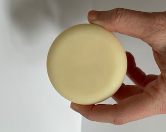 May include: A round, white, solid bar of shampoo.