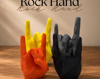 May include: Three geometric hand sculptures in orange, yellow, and black, each displaying the rock and roll hand gesture with a faceted, low-poly surface texture. The text "Rock Hand" is printed in black and script fonts above the objects.