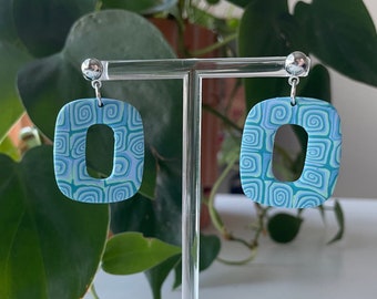 May include: A pair of blue and green swirl patterned dangle earrings with silver hooks.
