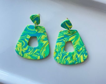May include: A pair of green and yellow marbled dangle earrings with a gold hook. The earrings are shaped like a rectangle with a cutout in the center.