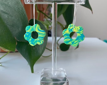 May include: A pair of green and yellow swirl flower dangle earrings. The earrings are made of polymer clay and have a silver hook.