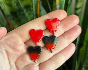 May include: Four heart-shaped embellishments with a dripping design. Two hearts are solid red, and two are black with a gradient to red. The hearts are glossy and appear to be made of resin or a similar material.