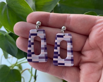 May include: A pair of geometric purple and white patterned earrings with silver posts.