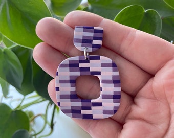 May include: Purple and pink checkered square-shaped dangle earrings with a smaller checkered square at the top.