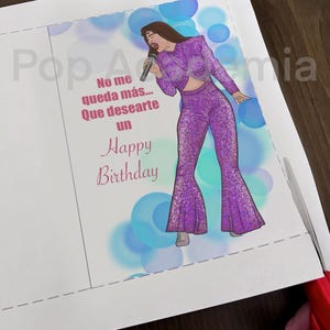 May include: A birthday card featuring a cartoon illustration of a woman singing into a microphone. The card has a blue and purple background with the text "No me queda m&aacute;s... Que desearte un Happy Birthday".