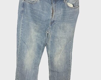 May include: Light blue denim jeans with a faded wash. The jeans have a classic five-pocket design, a zipper fly, and a brown waistband. The tag reads "PLUGS" and "38".