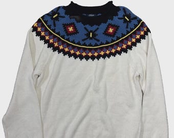 May include: Cream-colored sweater with a patterned yoke. The yoke features a geometric design in blue, red, yellow, and black. The sweater has long sleeves and a ribbed hem and cuffs. The brand name "CHAPS" is visible on the back of the neck.