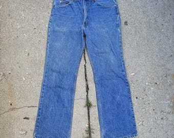 May include: Blue denim jeans with a classic five-pocket design. The jeans have a straight leg fit and a button and zipper closure. The denim has a faded wash, giving the jeans a vintage look. The jeans are made of a durable cotton blend.