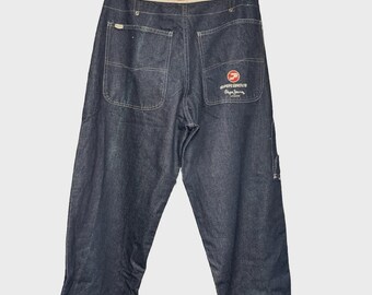 May include: Dark blue denim jeans with the "PEPE JEANS PERFORMANCE" logo on the waistband. The back pockets and a small pocket on the right leg are visible. The "PEPE JEANS" logo is also on the back pocket. The jeans are hanging from a hanger.